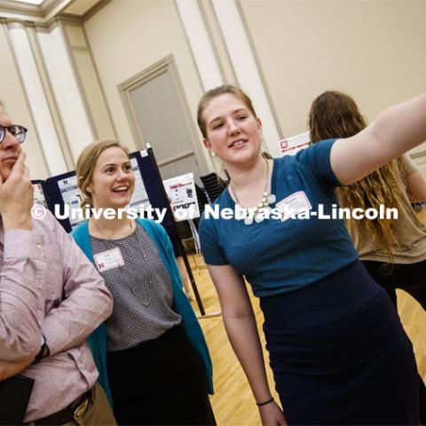 Gregory Bashford, left, and Lily Foley listen to Megan Ruckman present her poster. Undergraduate Spring Research Fair in the Union ballrooms. April 15, 2019. Photo by Craig Chandler / University Communication.