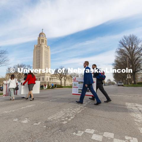 Undergrad students carry their posters from the Ferguson House to the Capitol Tuesday morning. Students presented their posters to multiple senators and then displayed the posters in the capitol. State Senators Research Fair at the Ferguson House. April 16, 2019. Photo by Craig Chandler / University Communication.