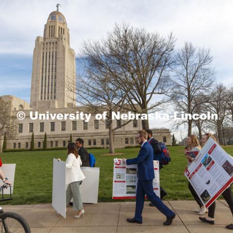 Undergrad students carry their posters from the Ferguson House to the Capitol Tuesday morning. Students presented their posters to multiple senators and then displayed the posters in the capitol. State Senators Research Fair at the Ferguson House. April 16, 2019. Photo by Craig Chandler / University Communication.