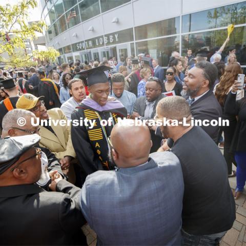 Friends, family and fellow Alpha Phi Alpha fraternity brothers form a circle around Davielle Phillips outside the arena following commencement. Phillips earned dual degrees of MBA and Master of Architecture. 2019 Spring Graduate Commencement in Pinnacle Bank Arena. May 3, 2019. Photo by Craig Chandler / University Communication