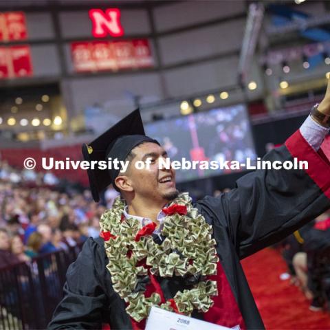 Bertin Jacobo waves to family and friends.  He wore a lei of money to commencement. Undergraduate commencement at Pinnacle Bank Arena, May 4, 2019. Photo by Craig Chandler / University Communication.