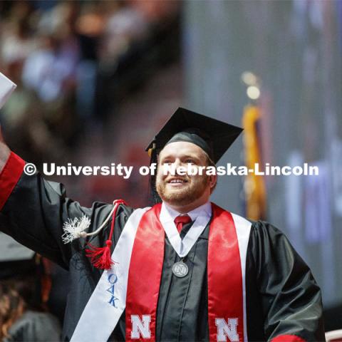 Cody McCain gestures to family and friends after receiving his College of Business diploma. Undergraduate commencement at Pinnacle Bank Arena, May 4, 2019. Photo by Craig Chandler / University Communication.