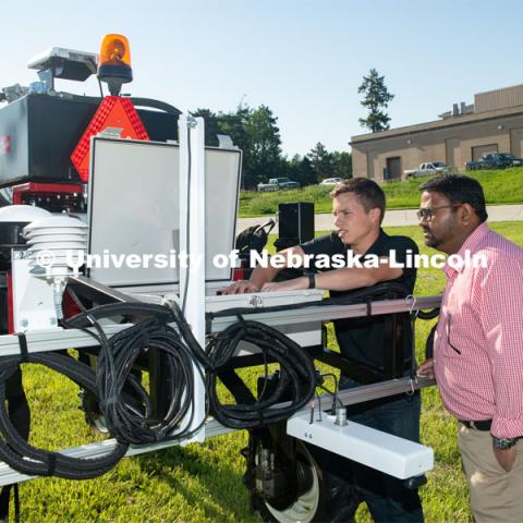 Grad student Josh Murman is with Santosh Pitla, associate professor of advanced machinery systems in the Department of Biological Systems Engineering at the University of Nebraska–Lincoln. Pitla is currently developing an autonomous tractor using ground robotics. Pitla and his team are testing their driverless tractor on the tractor testing field on East Campus. The autonomous tractors are named Flexible Structured Robotic Vehicle (FlexRo), the tractor is currently used for plant phenotyping, which is measuring the physical characteristics of the plant. According to Pitla, cameras are added to the machine to collect images that characterize plant conditions. Photo for the 2019 publication of the Strategic Discussions for Nebraska magazine. June 10, 2019, Photo by Gregory Nathan / University Communication. 