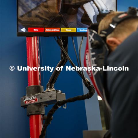 Studio manager Jerry Reif demonstrates the new virtual reality welding trainers. As he uses the non-functioning welding gun, his VR goggles gives a view of the welding that will occur. A screen on the machine allows other to watch and instruct. The virtual welders will be available to train aspiring welders. Nebraska Innovation Studio. June 14, 2019. Photo by Craig Chandler / University Communication.