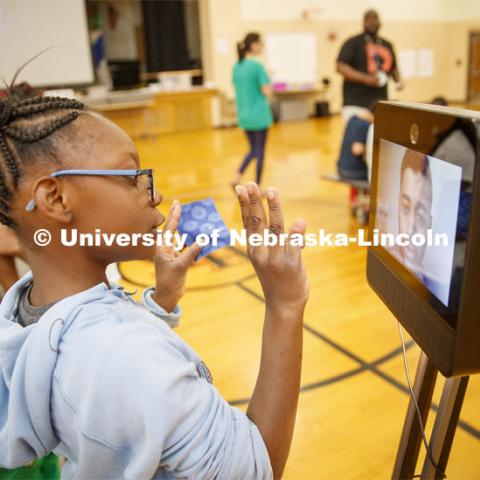 Ani'a Morris-Gordon interacts with Soham Patel, a UNL computer science major, who is using Beam technology to remote teach the class about nano technology and nano treated fabrics. Patel is able to not only video conference with the class but the screen is mounted on a robotic platform so he can wheel around the gym to help groups of students. Elementary-age students in Omaha's Kennedy Elementary learned about nano technology and water Wednesday afternoon. STEMentors is helping put on summer camps with Imagine Science. June 19, 2019. Photo by Craig Chandler / University Communication.