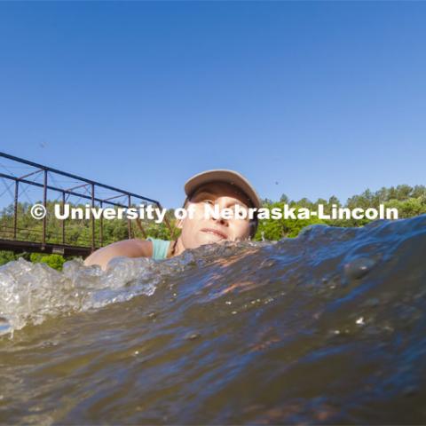 Kayla Vondracek, junior in Environmental Studies, fights the current and depth to take a sand sample as she researches algae in the Niobrara River. Jessica Corman, assistant professor in the School of Natural Resources, UCARE research group researching algae in the Niobrara River. Fort Niobrara National Wildlife Refuge. July 12, 2019. Photo by Craig Chandler / University Communication.