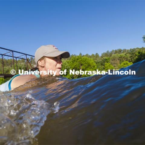 Kayla Vondracek, junior in Environmental Studies, fights the current and depth to take a sand sample as she researches algae in the Niobrara River. Jessica Corman, assistant professor in the School of Natural Resources, UCARE research group researching algae in the Niobrara River. Fort Niobrara National Wildlife Refuge. July 12, 2019. Photo by Craig Chandler / University Communication.