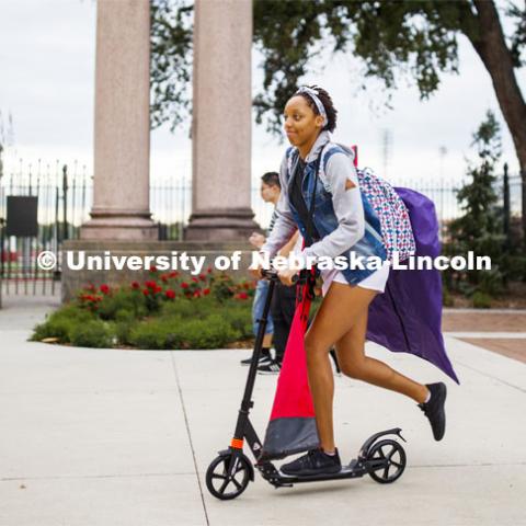 Alissa Clarke is loaded down with her flag team gear as she scooters her way to Wednesday evening's Cornhusker Marching Band practice in Memorial Stadium. City Campus. August 21, 2019. Photo by Craig Chandler / University Communication.
