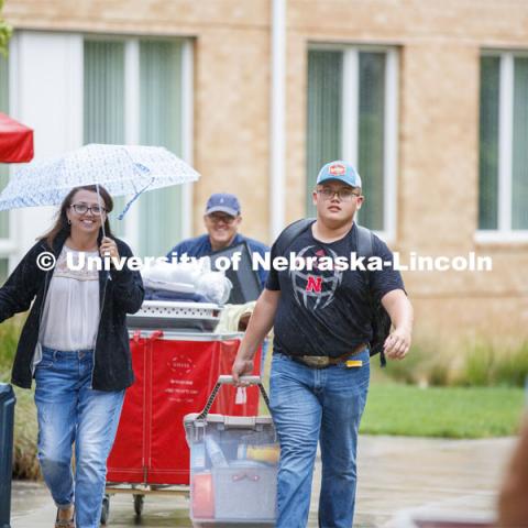 Tristan Smith carries his belongings as he moves in with the help of mom, Tina, and dad, Doug.  They are from Curtis, Nebraska. Massengale Residential Center move in. August 21, 2019. Photo by Craig Chandler / University Communication.