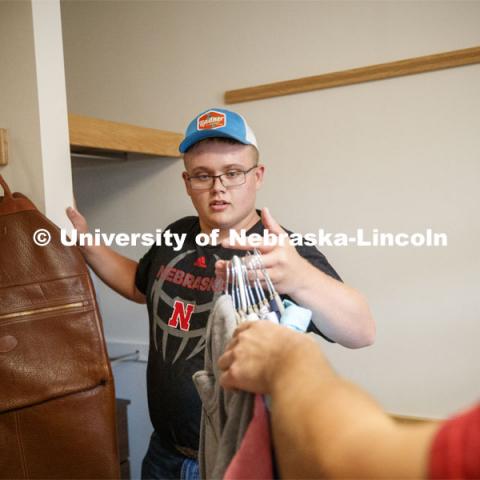 Tristan Smith, from Curtis, Nebraska, grabs a handful of clothes to hang. Massengale Residential Center move in. August 21, 2019. Photo by Craig Chandler / University Communication.