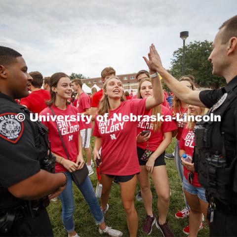 Officer Craig Tepley high-fives Lauren Lintner of Chicago after he explained why the game Corn Hole is called that in Nebraska. Officers Terrell Long Jr. and Craig Tepley were challenged to a game by Hebron students McKenzie Johnson and Emily Welch. The Hebron duo won. Big Red Welcome, Chancellor's BBQ for incoming freshman and new students on the greenspace by the Memorial Union. August 23, 2019. Photo by Craig Chandler / University Communication.