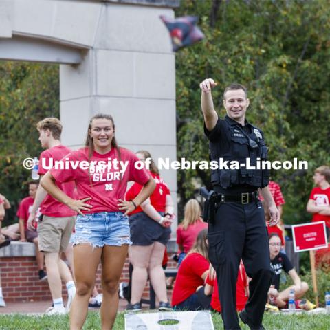 UNL Police Officer Craig Tepley shows his corn hole form at the picnic. He and fellow officer Terrell Long Jr. were challenged to a game by Hebron students Emily Welch, at left, and McKenzie Johnson. The Hebron duo won. Big Red Welcome, Chancellor's BBQ for incoming freshman and new students on the greenspace by the Memorial Union. August 23, 2019. Photo by Craig Chandler / University Communication.