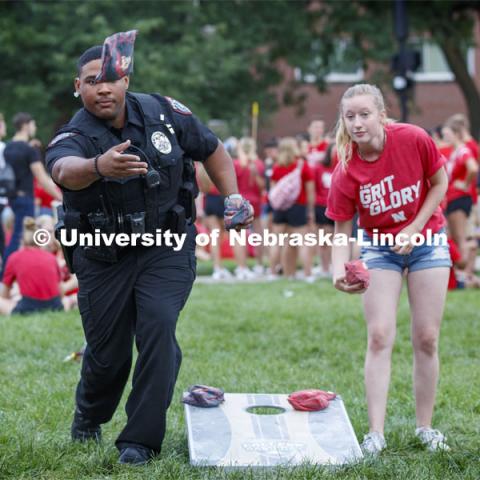 UNL Police Officer Terrell Long Jr. shows his corn hole form at the picnic. He and fellow officer Craig Tepley were challenged to a game by Hebron students McKenzie Johnson, at right, and Emily Welch. The Hebron duo won. Big Red Welcome, Chancellor's BBQ for incoming freshman and new students on the greenspace by the Memorial Union. August 23, 2019. Photo by Craig Chandler / University Communication.