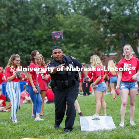 UNL Police Officer Terrell Long Jr. shows his corn hole form at the picnic. He and fellow officer Craig Tepley were challenged to a game by Hebron students McKenzie Johnson, at right, and Emily Welch. The Hebron duo won. Big Red Welcome, Chancellor's BBQ for incoming freshman and new students on the greenspace by the Memorial Union. August 23, 2019. Photo by Craig Chandler / University Communication.