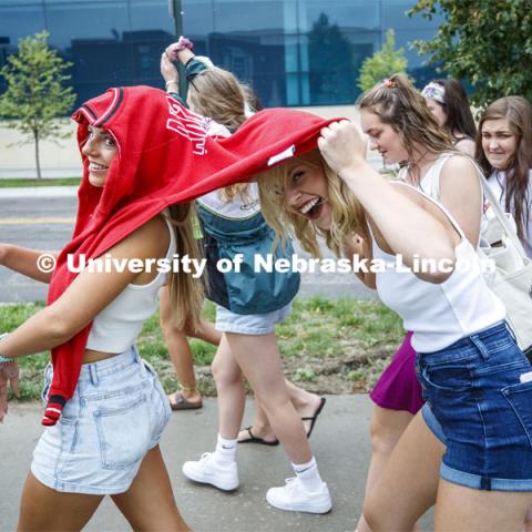 Valerie Bohuslavsky of David City, NE, shares her hoodie with Savannah Gerlack of DeWitt, NE, as the two try to keep dry as they walk in the rain between the Rho Gamma Reveal and the Bid Day activities. Sorority Bid Day. August 24, 2019. Photo by Craig Chandler / University Communication.