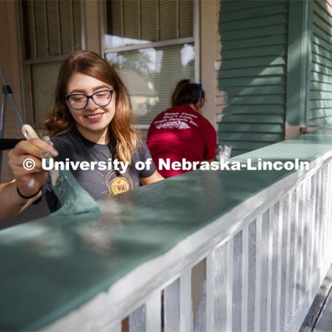 Deena Keilany of Omaha paints the porch rail of a home at 30th and Vine. First year law students, faculty and staff paint two Lincoln houses. The painting is a yearly tradition for the incoming students. August 24, 2019. Photo by Craig Chandler / University Communication.