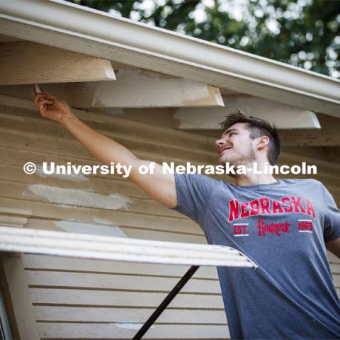 Matt Karnes of Hastings primes under the eaves of a house at 30th and Vine. First year law students, faculty and staff paint two Lincoln houses. The painting is a yearly tradition for the incoming students. August 24, 2019. Photo by Craig Chandler / University Communication.