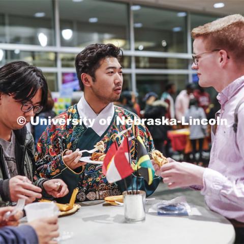 William Yao, center, talks with Andrew Neill as they sample food at the festival. Yao is wearing the undergarment for a Chinese Ming Dynasty court clothing. Global Huskers Festival, a multicultural festival provides attendees the chance to explore the world through informational booths that will have food, cultural décor, art, and more, each hosted by UNL students from those culture. November 19, 2019. Photo by Craig Chandler / University Communication.