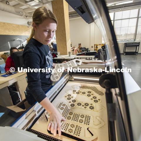 Carly Brotherson pulls sock blocks from the laser cutter at Nebraska Innovation Studio Nov. 25. Brotherson made the sock blocks for a yarn store, which requested the project through the new 'Request a Maker' button, which matches makers to projects. November 25, 2019. Photo by Greg Nathan / University Communication.