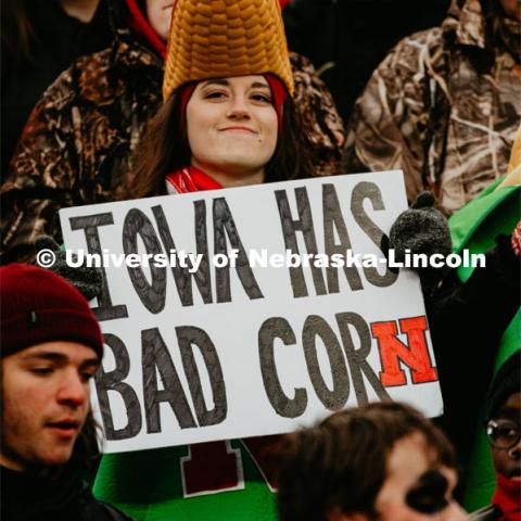 A Nebraska student decked out in her corn hat holds a sign saying Iowa has bad corn. Nebraska vs. Iowa State University football game. November 29, 2019. Photo by Justin Mohling / University Communication.