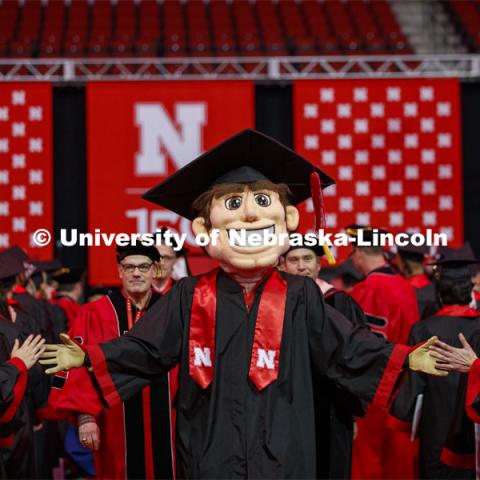 Herbie Husker, decked out in his graduation cap and gown, high fives graduates as they leave the arena. December Undergraduate commencement at Pinnacle Bank Arena. December 21, 2019. Photo by Craig Chandler / University Communication.