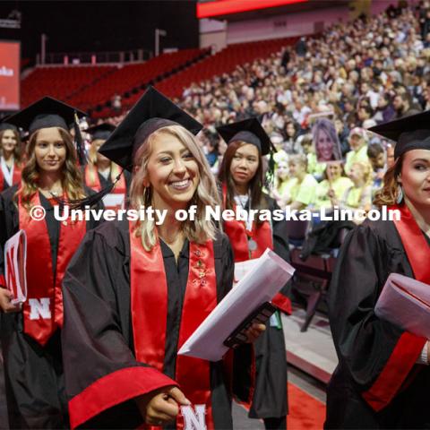 Alyssa Arndt smiles as she walks past her family cheering section. The family all wore neon green shirts so Alyssa wouldn't miss seeing them. December Undergraduate commencement at Pinnacle Bank Arena. December 21, 2019. Photo by Craig Chandler / University Communication.