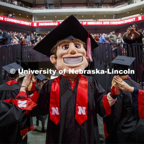 Herbie Husker, decked out in his graduation cap and gown, high fives graduates as they leave the arena. December Undergraduate commencement at Pinnacle Bank Arena. December 21, 2019. Photo by Craig Chandler / University Communication.