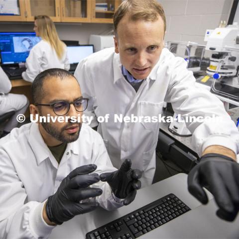 Ryan Pedrigi (right), Assistant Professor in Department of Mechanical and Materials Engineering, College of Engineering, discuss a microscope image with graduate student Jaideep Sahni. In the background is graduate student Morgan Schake and undergraduate researcher Ian McCue. March 13, 2020. Photo by Craig Chandler / University Communication.