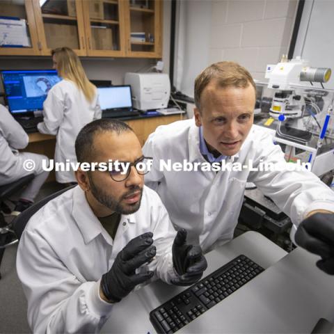 Ryan Pedrigi (right), Assistant Professor in Department of Mechanical and Materials Engineering, College of Engineering, discuss a microscope image with graduate student Jaideep Sahni. In the background is graduate student Morgan Schake and undergraduate researcher Ian McCue. March 13, 2020. Photo by Craig Chandler / University Communication.