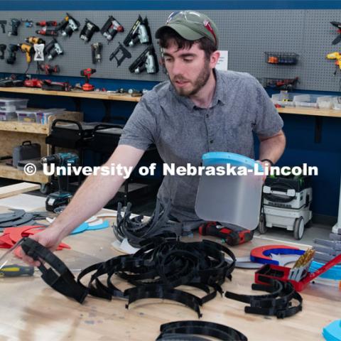 Max Wheeler, Shop Instructional Technician at Nebraska Innovation Studio, assembles face shields with parts made at NIC. Face shields have been assembled from 3-D printed and laser-cut parts, and now, injection molding will be used to mass-produce parts for face shields. The face shields are being assembled for hospitals in Nebraska in response to COVID-19. April 1, 2020. Photo by Gregory Nathan / University Communication.