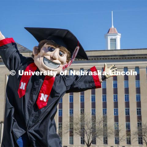 Herbie Husker leaps for joy on the lawn in front of Love Library and is decked out in graduation attire for the Spring Commencement that was which streamed online and aired on NET because of the COVID-19 pandemic. April 10, 2020. Photo by Craig Chandler / University Communication.