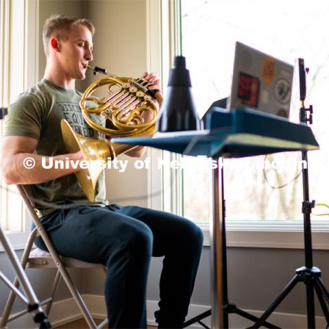 Justin Mohling, a second year master’s student, plays his French horn while remote learning in his Lincoln Apartment. April 11, 2020. Photo by Justin Mohling / University Communication.