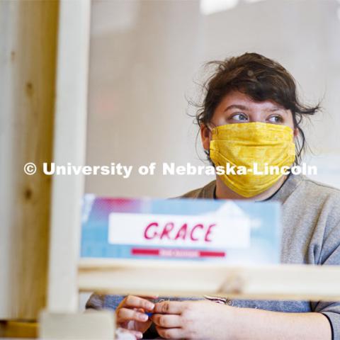 Grace Ellis, a sophomore in secondary education from Waverly, Nebraska, stayed on campus to serve as a resident assistant and work as a desk assistant in University Suites. She wears a mask while she works the desk in University Suites. She is one of many students still working on campus. April 13, 2020. Photo by Craig Chandler / University Communication.