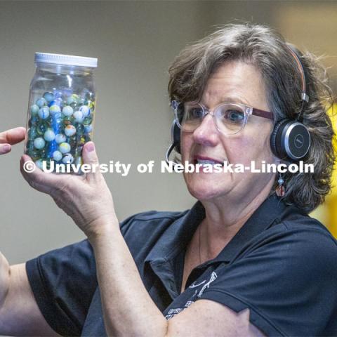 Annie Mumgaard, Virtual Learning Coordinator for the University Museum, uses a jar full of marbles to describe how individual rocks, like the marbles, can then be transformed by heat and pressure into metamorphic rock. April 14, 2020. Photo by Craig Chandler / University Communication.