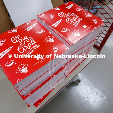 Printing Service employees work to fill the Go Big Grad boxes. Graduates will receive a "Go Big Grad" box before May 9. The box will include a complimentary mortarboard or tam, along with other surprises. April 24, 2020. Photo by Craig Chandler / University Communication.