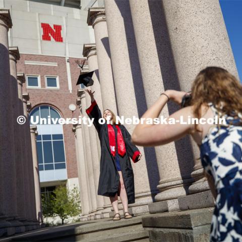 Rose Wehrman, senior in English, from Kenesaw, NE, is photographed by Sarah Schilling, senior in marketing from Omaha. The two borrowed a cap and gown (from a friend who graduated last year) to take photos of each other on campus Thursday morning. April 30, 2020. Photo by Craig Chandler / University Communication.