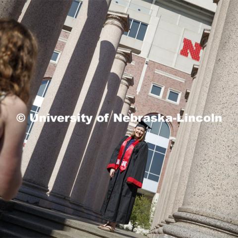 Rose Wehrman, senior in English, from Kenesaw, NE, is photographed by Sarah Schilling, senior in marketing from Omaha. The two borrowed a cap and gown (from a friend who graduated last year) to take photos of each other on campus Thursday morning. April 30, 2020. Photo by Craig Chandler / University Communication.