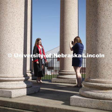 Sarah Schilling, senior in marketing from Omaha, is photographed by Rose Wehrman, senior in English, from Kenesaw, NE. The two borrowed a cap and gown (from a friend who graduated last year) to take photos of each other on campus Thursday morning. April 30, 2020. Photo by Craig Chandler / University Communication.