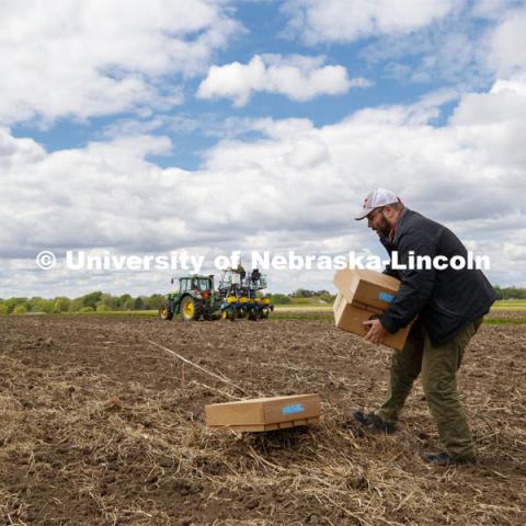 James Schnable positions boxes of seed packets in the field to speed up the planting process. James Schnable corn research group plants at agronomy fields at 84th and Havelock in northeast Lincoln. Schnable’s lab studies grain DNA to find the best varieties for breeding and genetic modification to help with traits including yields and drought resistance. The 2.5-acre plot was being planted with 752 genotypes in 1680 precisely randomized plots. To plant those plots along with a check genotype, the researchers used 1860 packets of seeds manually poured into a hopper every 7 seconds while sitting atop a custom research planter. May 6, 2020. Photo by Craig Chandler / University Communication.