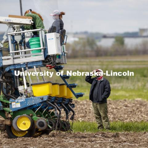 James Schnable talks with Research Manager Christine Smith and Brandi Sigmon, Assistant Professor of practice in Plant Pathology, during a break in the planting. James Schnable corn research group plants at agronomy fields at 84th and Havelock in northeast Lincoln. Schnable’s lab studies grain DNA to find the best varieties for breeding and genetic modification to help with traits including yields and drought resistance. The 2.5-acre plot was being planted with 752 genotypes in 1680 precisely randomized plots. To plant those plots along with a check genotype, the researchers used 1860 packets of seeds manually poured into a hopper every 7 seconds while sitting atop a custom research planter. May 6, 2020. Photo by Craig Chandler / University Communication.