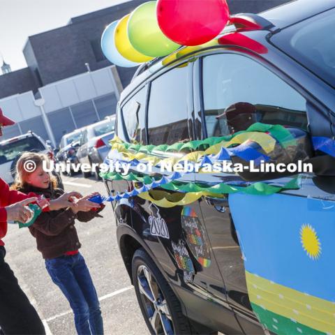 Ratch O'Connell and his granddaughter, Elisa Peters, decorate their vehicle before the parade. Blue, yellow and green balloons and streamers, the national colors of Rwanda, along with Husker Red decorated many of the vehicles. Christ Place Church families gave the Rwandan students a vehicle parade to help celebrate the graduates and undergraduates. The church has been host families for about 25 of the 50 Rwandan students who are graduating. They also provided fall and spring event off-campus marking the beginning and ending of each school year along with rides from campus to church and back each Sunday. The group of host families had been planning a graduation party for the students until COVID-19 occurred. Because of COVID-19, the group has planned for a socially distanced “parade” of host family vehicles that circled University Suites on R Street. May 8, 2020. Photo by Craig Chandler / University Communication.