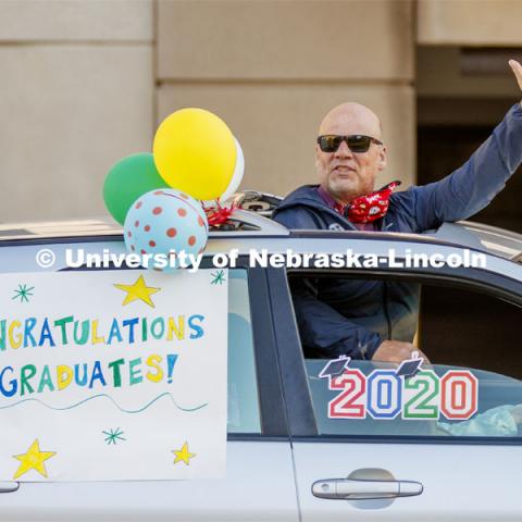 Brad Novasad uses the sunroof to wave to the students. Christ Place Church families gave the Rwandan students a vehicle parade to help celebrate the graduates and undergraduates. The church has been host families for about 25 of the 50 Rwandan students who are graduating. They also provided fall and spring event off-campus marking the beginning and ending of each school year along with rides from campus to church and back each Sunday. The group of host families had been planning a graduation party for the students until COVID-19 occurred. Because of COVID-19, the group has planned for a socially distanced “parade” of host family vehicles that circled University Suites on R Street. May 8, 2020. Photo by Craig Chandler / University Communication.