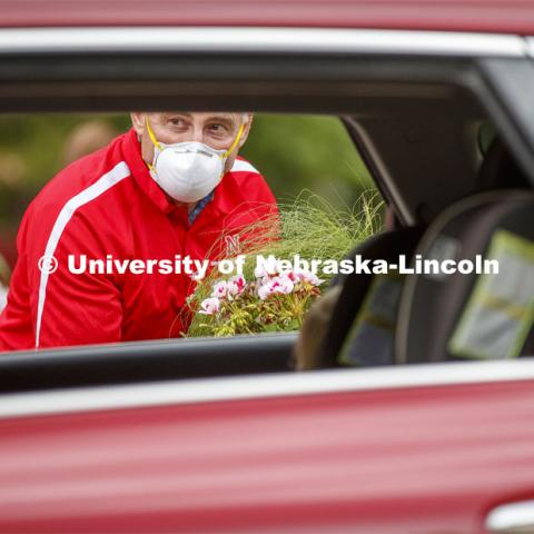 Stacy Adams, Associate Professor of Practice for Agronomy and Horticulture, waits for a driver to unlock the rear hatch so he can set a flat of flowers in the SUV. The University of Nebraska-Lincoln Horticulture Club hosted its first-ever plant giveaway Thursday, a replacement for the club's annual plant sale and fundraiser was due to the university shutdown in response to the global pandemic in mid-March. A prepackaged assortment of plants in a cardboard flat will be ready for each recipient. There were two sessions of giveaways with 100 flats of plants at each one. It only took 22 minutes to give away the morning allocation of flats. May 21, 2020. Photo by Craig Chandler / University Communication.