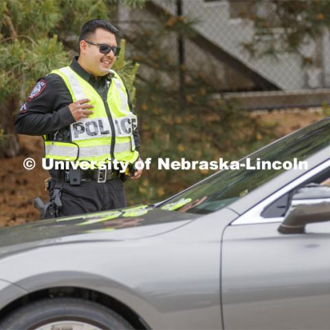 UNL Police Officer Anderson Delgado directs the huge traffic flow for people coming for the free flat of flowers left from the Horticulture Club Plant Sale. May 21, 2020. Photo by Craig Chandler / University Communication.