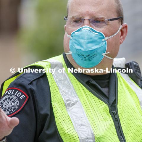 UNL Police Officer Paul Schmeling directs the huge traffic flow for people coming for the free flat of flowers left from the Horticulture Club Plant Sale. May 21, 2020. Photo by Craig Chandler / University Communication.