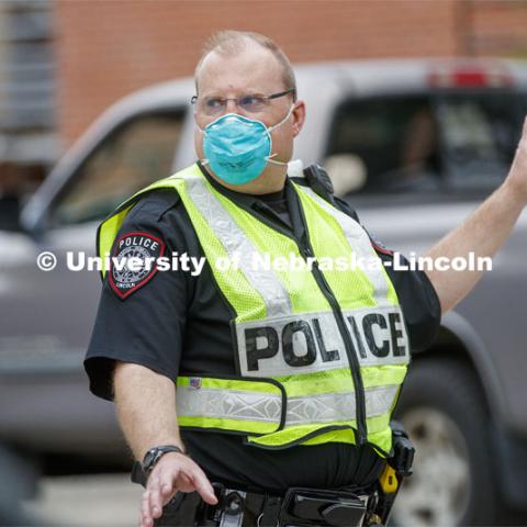 UNL Police Officer Paul Schmeling directs the huge traffic flow for people coming for the free flat of flowers left from the Horticulture Club Plant Sale. May 21, 2020. Photo by Craig Chandler / University Communication.