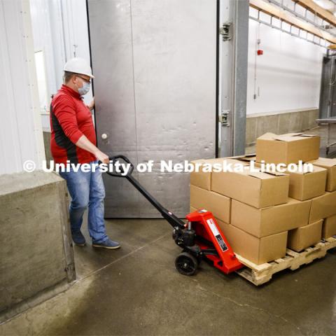 Gary Sullivan, Associate Professor in Animal Science, pulls a pallet load of processed pork toward the awaiting Lincoln Food Bank truck. UNL's Loeffel Meat Laboratory in partnership with the Nebraska Pork Producers Association Pork Cares program has donated more than 1300 pounds of processed pork to the Lincoln Food Bank. The pigs were donated by Niewohner Brothers of Albion, NE, and the pigs were harvested and processed at the east campus meat lab. May 26, 2020. Photo by Craig Chandler / University Communication.