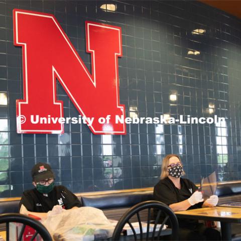 Dinning Services employees, Rochan Pinho, Janet Nichols and Dami Olsen, assemble face shields at Harper Dining Center. Once school starts up, they will use the shields for prevention of the spread of COVID-19. April 28, 2020. Photo by Gregory Nathan / University Communication.