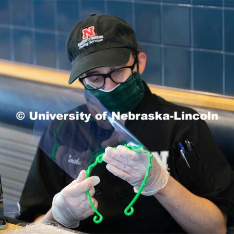 Dinning Services employees, Rochan Pinho, Janet Nichols and Dami Olsen, assemble face shields at Harper Dining Center. Once school starts up, they will use the shields for prevention of the spread of COVID-19. April 28, 2020. Photo by Gregory Nathan / University Communication.