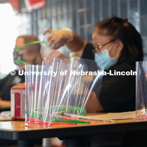 Dinning Services employees, Rochan Pinho, Janet Nichols and Dami Olsen, assemble face shields at Harper Dining Center. Once school starts up, they will use the shields for prevention of the spread of COVID-19. April 28, 2020. Photo by Gregory Nathan / University Communication.